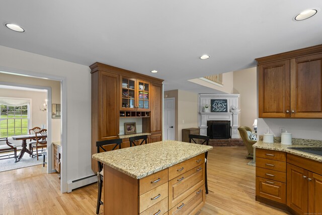 2 Applewood Cmn, East Lyme, CT 06333 - kitchen with light wood finished floors, a fireplace, light stone countertops, glass insert cabinets, and a kitchen breakfast bar