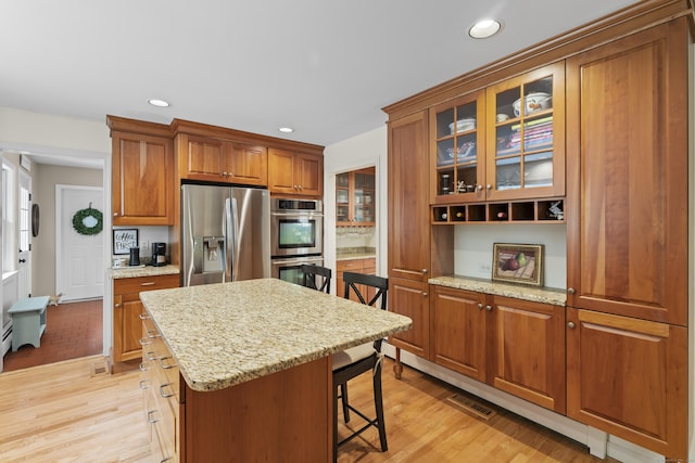2 Applewood Cmn, East Lyme, CT 06333 - kitchen featuring stainless steel appliances, a breakfast bar area, light wood-type flooring, glass insert cabinets, and brown cabinets