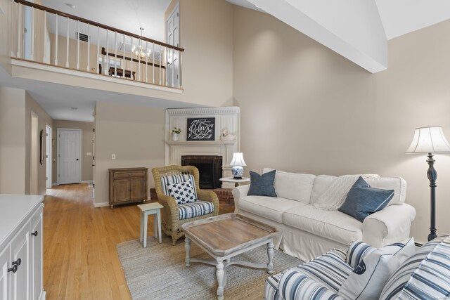 2 Applewood Cmn, East Lyme, CT 06333 - living room featuring high vaulted ceiling, light wood finished floors, a fireplace, and a chandelier