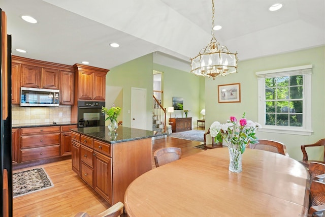 41 White Birch Dr, Trumbull, CT 06611 - kitchen with stainless steel microwave, black oven, light wood-type flooring, a chandelier, and decorative backsplash
