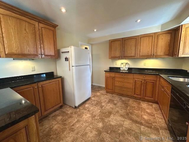 15 Bargate Rd, Clinton, CT 06413 - kitchen with freestanding refrigerator, black dishwasher, brown cabinetry, recessed lighting, and dark stone countertops