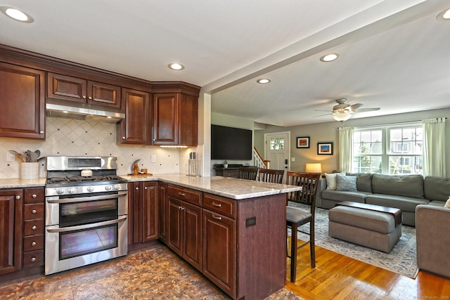 30 Wilcox Rd, Milford, CT 06460 - kitchen featuring double oven range, a breakfast bar, under cabinet range hood, a peninsula, and tasteful backsplash