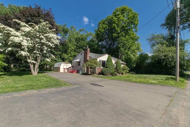 26 Hunt Ln, East Haven, CT 06512 - view of front of home featuring a storage unit, a chimney, a front lawn, and view of scattered trees