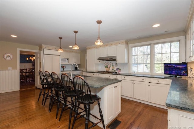 300 Ridgefield Rd, Wilton, CT 06897 - kitchen with white microwave, dark wood finished floors, a breakfast bar, an island with sink, and a wainscoted wall