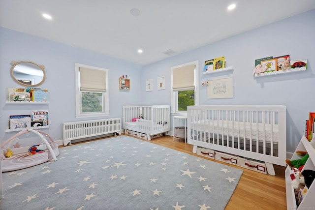161 Crestwood Rd, Fairfield, CT 06824 - bedroom featuring radiator heating unit, wood finished floors, a crib, and recessed lighting
