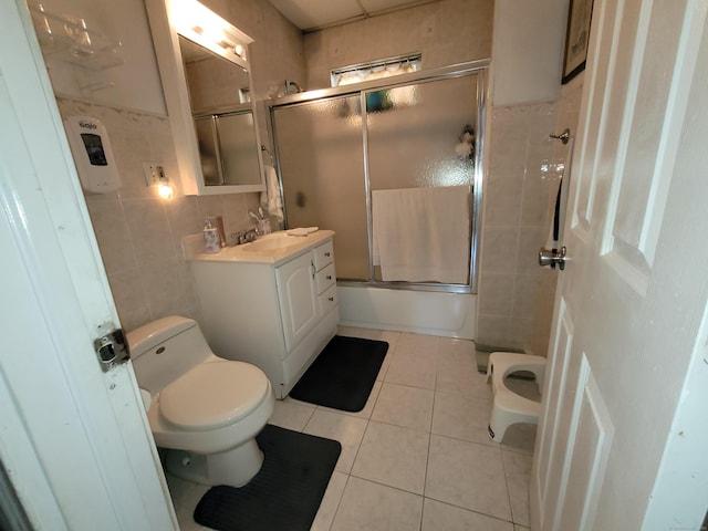 73 Newfield Ave, Bridgeport, CT 06607 - bathroom with tile walls, tile patterned flooring, vanity, and combined bath / shower with glass door