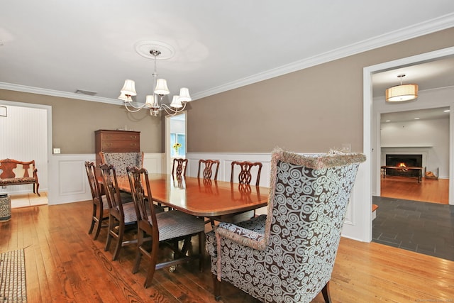 63 Pipers Hill Rd, Wilton, CT 06897 - dining area with crown molding, a chandelier, a wainscoted wall, wood-type flooring, and a lit fireplace
