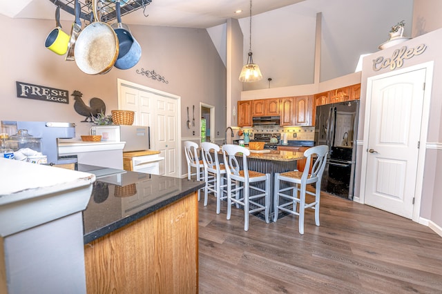 80 Richard Ave, Wolcott, CT 06716 - kitchen with freestanding refrigerator, high vaulted ceiling, under cabinet range hood, tasteful backsplash, and brown cabinets