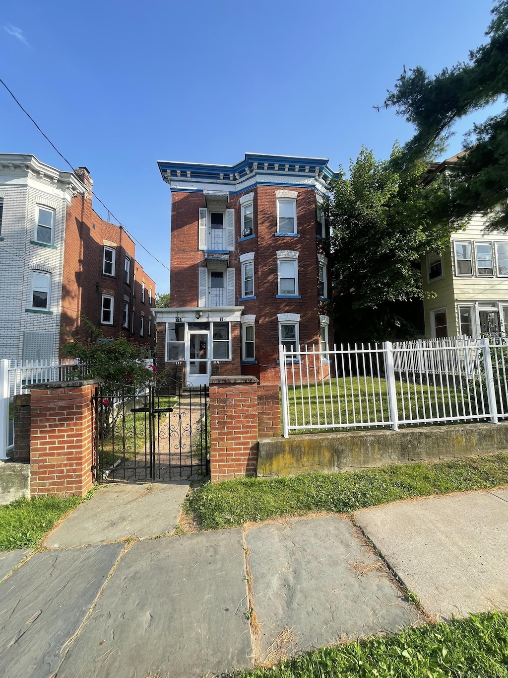 117 Shultas Pl, Hartford, CT 06114 - view of front facade with brick siding, a fenced front yard, and a gate