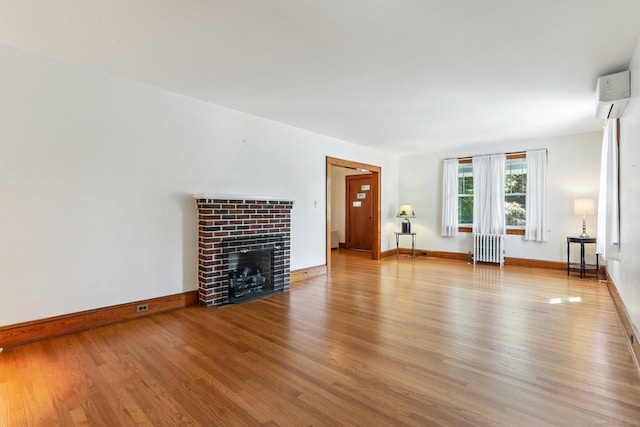 12 Lincoln Ave, Danbury, CT 06810 - unfurnished living room featuring radiator heating unit, a wall mounted AC, wood finished floors, and a fireplace