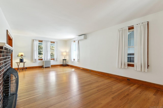 12 Lincoln Ave, Danbury, CT 06810 - unfurnished living room with radiator, a fireplace, light wood-style flooring, and a wall mounted air conditioner