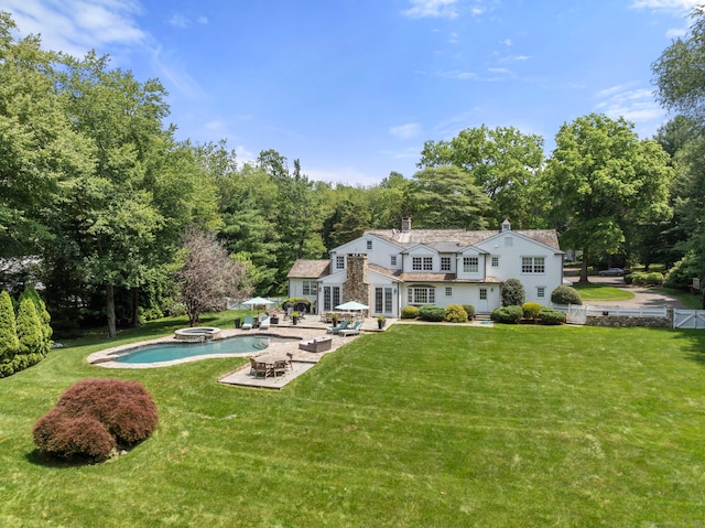 92 Hornbeam Rd, Fairfield, CT 06824 - rear view of house featuring a gambrel roof, a patio, a lawn, a chimney, and a pool with connected hot tub