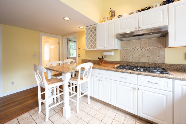 117 Long Meadow Hill Rd, Brookfield, CT 06804 - kitchen with stainless steel gas cooktop, under cabinet range hood, light tile patterned floors, white cabinets, and backsplash