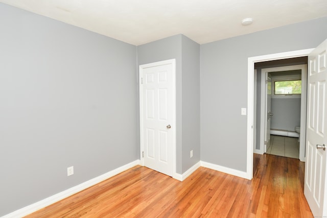129 Tomlinson Ave, Plainville, CT 06062 - unfurnished bedroom with light wood-style flooring and a baseboard heating unit