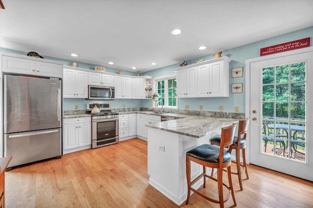 18 Overlook Ave, Middletown, CT 06457 - kitchen with appliances with stainless steel finishes, a peninsula, white cabinetry, light wood-style floors, and recessed lighting