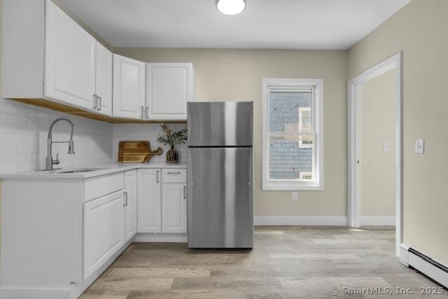 85 Twiss St, Meriden, CT 06450 - kitchen featuring freestanding refrigerator, baseboard heating, white cabinetry, light wood-style floors, and light countertops