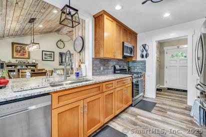 92 Seminole Ln Unit B, Stratford, CT 06614 - kitchen with appliances with stainless steel finishes, light stone counters, vaulted ceiling, light wood finished floors, and hanging light fixtures