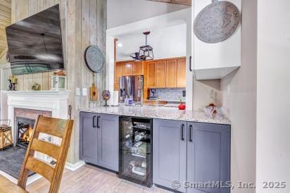 92 Seminole Ln Unit B, Stratford, CT 06614 - bar featuring stainless steel fridge, beverage cooler, backsplash, light wood-style floors, and a warm lit fireplace