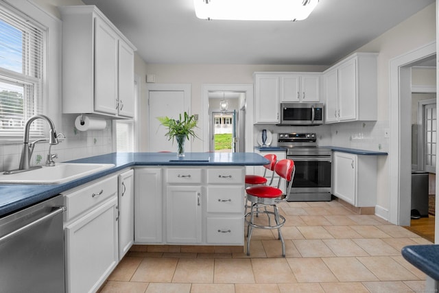 14 Maple St, Darien, CT 06820 - kitchen featuring appliances with stainless steel finishes, a peninsula, backsplash, and white cabinets