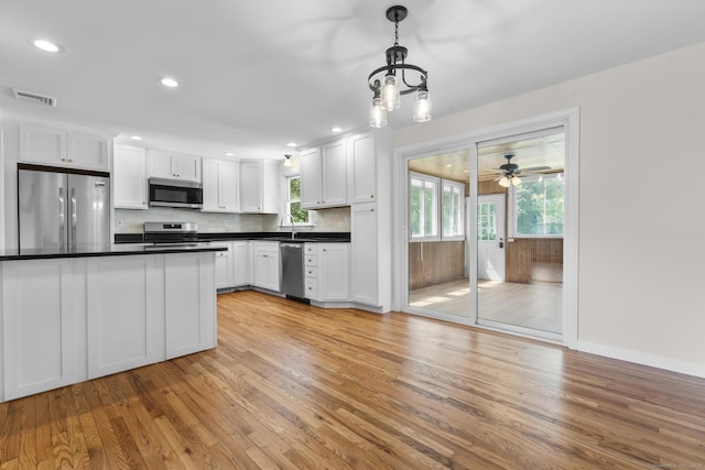 66 Pinnacle Rd, Bristol, CT 06010 - kitchen featuring stainless steel appliances, light wood-style flooring, dark countertops, white cabinets, and decorative light fixtures