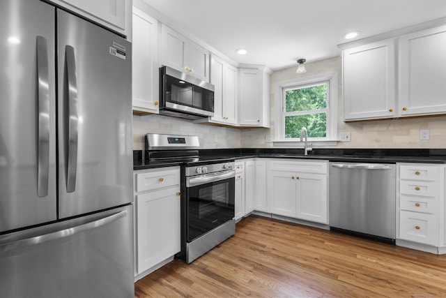 66 Pinnacle Rd, Bristol, CT 06010 - kitchen featuring appliances with stainless steel finishes, dark countertops, light wood finished floors, white cabinets, and recessed lighting