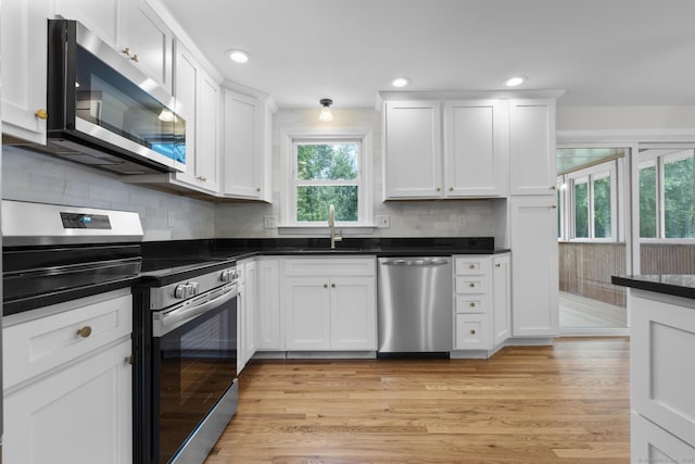 66 Pinnacle Rd, Bristol, CT 06010 - kitchen with appliances with stainless steel finishes, dark countertops, white cabinetry, backsplash, and light wood finished floors