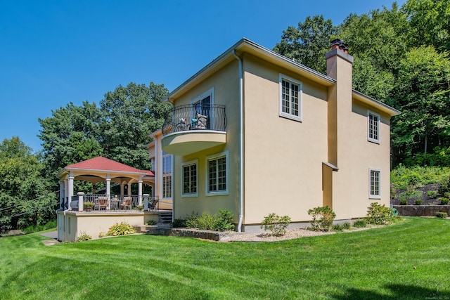 2 Barberry Ln, Farmington, CT 06032 - rear view of house featuring a balcony, a chimney, a lawn, a gazebo, and stucco siding