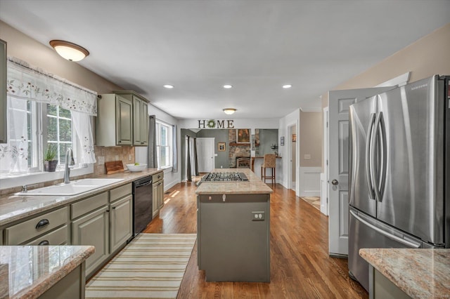 42 Woodmont Cir, East Haddam, CT 06423 - kitchen featuring appliances with stainless steel finishes, a kitchen island, wood finished floors, light stone countertops, and a wainscoted wall