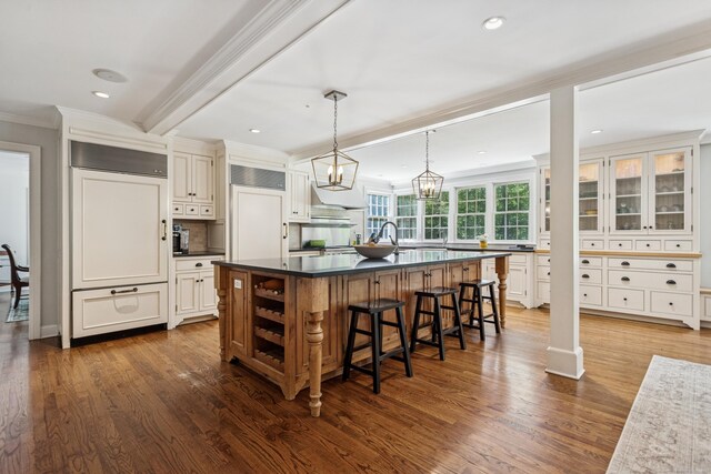 47 Tubbs Spring Dr, Weston, CT 06883 - kitchen with paneled built in fridge, ornamental molding, dark countertops, a kitchen breakfast bar, and an island with sink