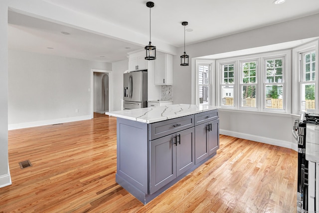 108 Adams St, New Britain, CT 06052 - kitchen with stainless steel fridge, gray cabinetry, light wood finished floors, arched walkways, and light stone counters