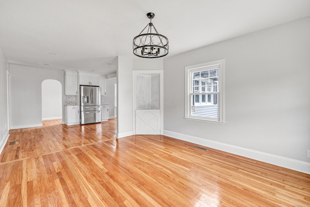 108 Adams St, New Britain, CT 06052 - unfurnished living room featuring arched walkways, light wood-style flooring, and a chandelier