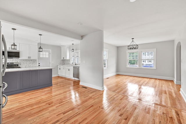 108 Adams St, New Britain, CT 06052 - kitchen featuring appliances with stainless steel finishes, light wood finished floors, white cabinetry, backsplash, and pendant lighting