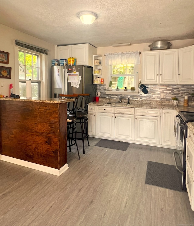 30 Roulin St, Torrington, CT 06790 - kitchen featuring electric range, light wood-style floors, white cabinetry, and a textured ceiling
