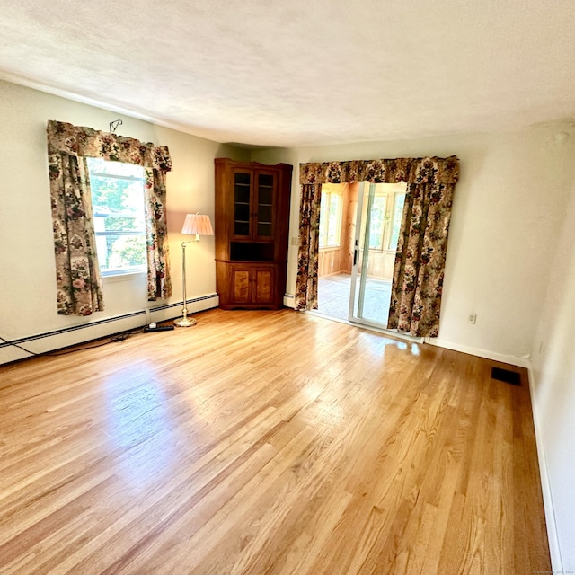 191 Prospect Hill Rd, Groton, CT 06340 - unfurnished living room featuring plenty of natural light, light wood finished floors, a baseboard heating unit, and a textured ceiling