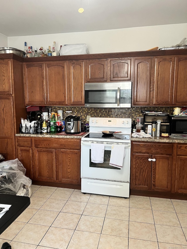 70 Burnham St, Hartford, CT 06112 - kitchen with stainless steel microwave, white electric range oven, backsplash, and light tile patterned floors