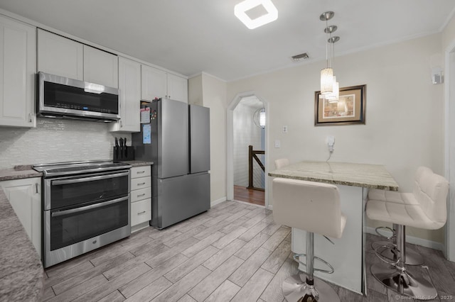 1996 Straits Tpke, Middlebury, CT 06762 - kitchen with appliances with stainless steel finishes, white cabinets, light wood-style flooring, backsplash, and hanging light fixtures