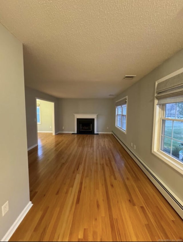 126 Sunnydale Ave, Bristol, CT 06010 - unfurnished living room featuring baseboard heating, wood finished floors, a textured ceiling, and a fireplace