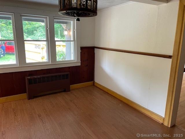 574 Cutlers Farm Rd, Monroe, CT 06468 - empty room featuring radiator heating unit, plenty of natural light, light wood-style floors, and ornamental molding