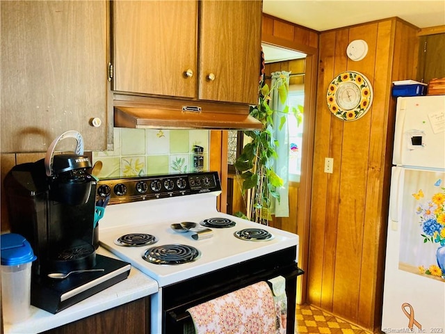 44 Cheyenne Rd, East Hartford, CT 06118 - kitchen with range with electric cooktop, freestanding refrigerator, under cabinet range hood, wooden walls, and brown cabinets
