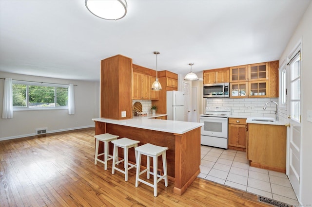 10 John Smith Dr, West Hartford, CT 06107 - kitchen featuring white appliances, a peninsula, brown cabinetry, and tasteful backsplash