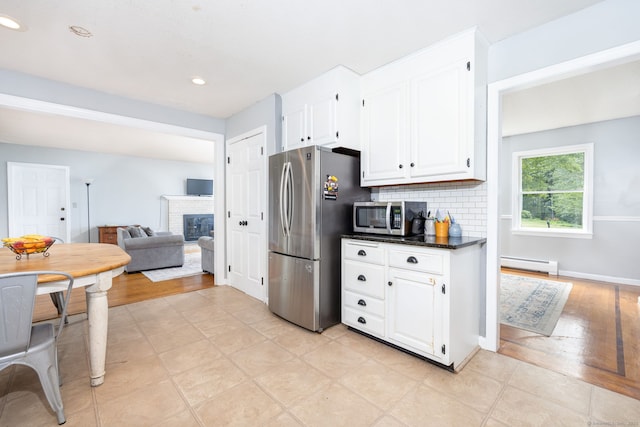 55 Charles Mary Dr, East Hampton, CT 06424 - kitchen featuring stainless steel appliances, baseboard heating, white cabinetry, a fireplace, and backsplash