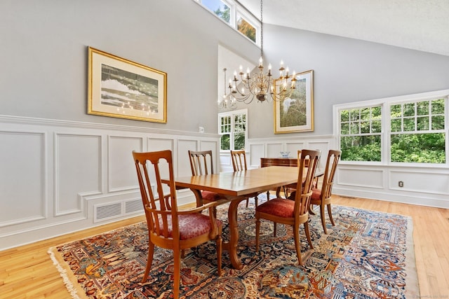 91 Fox Run Rd, New Canaan, CT 06840 - dining room featuring a decorative wall, a chandelier, light wood-style floors, high vaulted ceiling, and wainscoting