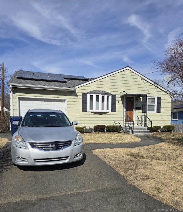 26 Susquehanna Ave, West Haven, CT 06516 - view of front of house featuring asphalt driveway, roof mounted solar panels, an attached garage, and roof with shingles