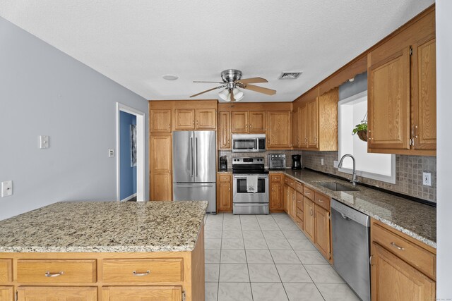 8 Barbara Ln, Southington, CT 06479 - kitchen featuring stainless steel appliances, backsplash, ceiling fan, light stone countertops, and brown cabinetry