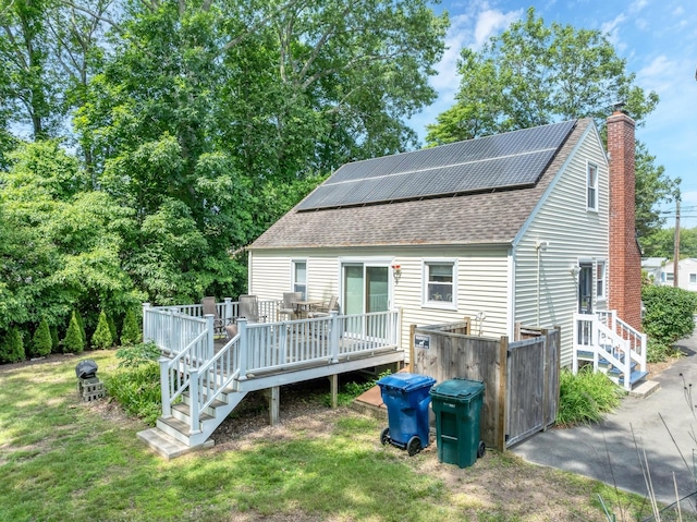 15 Hawks Nest Rd, Old Lyme, CT 06371 - rear view of property featuring a shingled roof, solar panels, a chimney, a wooden deck, and a lawn