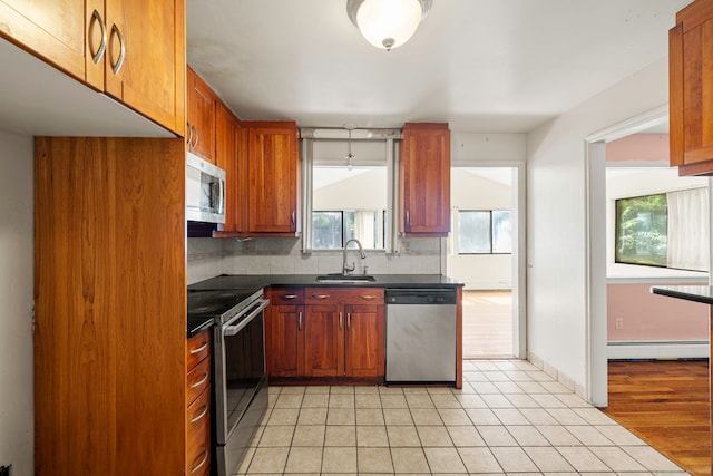 21 Gilbert Hill Rd, Norwalk, CT 06853 - kitchen featuring stainless steel appliances, dark countertops, decorative backsplash, a baseboard radiator, and light tile patterned flooring