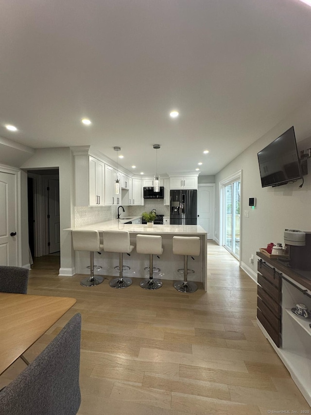 60 Carlson Ave, Bridgeport, CT 06606 - kitchen with black fridge, stainless steel microwave, a breakfast bar, white cabinetry, and decorative backsplash