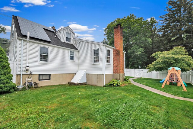 1462 Cutspring Rd, Stratford, CT 06614 - back of property with a chimney, a fenced backyard, a playground, and roof mounted solar panels