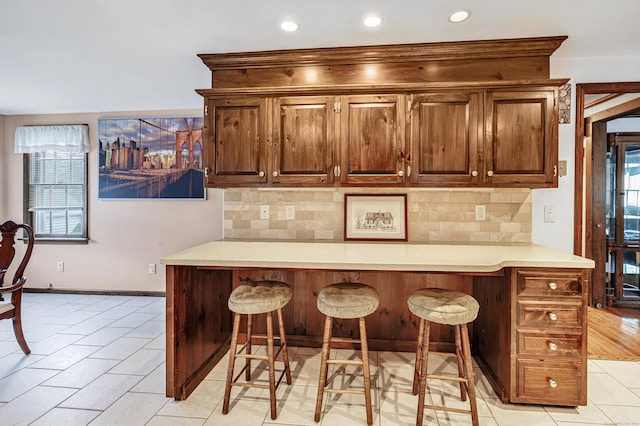 1462 Cutspring Rd, Stratford, CT 06614 - kitchen featuring a kitchen bar, recessed lighting, tasteful backsplash, light countertops, and light tile patterned flooring