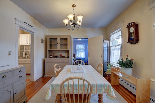 32 Columbus St, East Hartford, CT 06108 - dining room featuring a chandelier, light wood-style floors, and a baseboard heating unit